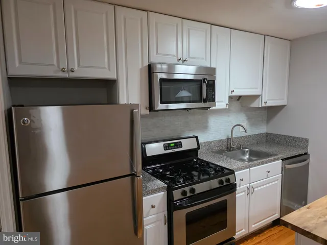 a kitchen with granite countertop white cabinets and stainless steel appliances