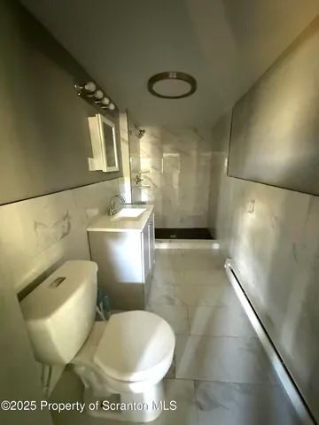 a white toilet sitting next to a bathroom sink and a shower