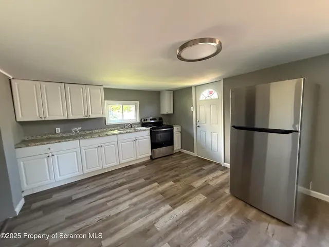 a kitchen with granite countertop a refrigerator sink and cabinets