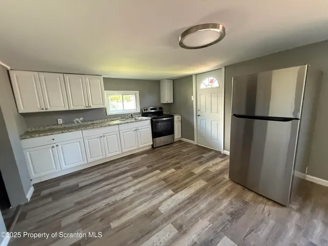 a kitchen with a refrigerator a sink and dishwasher with wooden floor