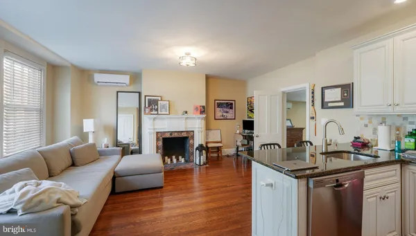 a living room with stainless steel appliances a dining table chairs and a refrigerator