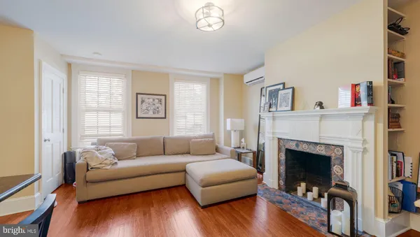 a living room with stainless steel appliances furniture a fireplace a flat screen tv and kitchen view