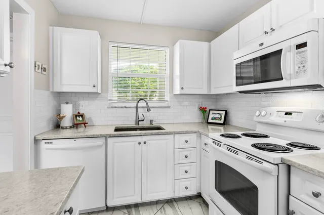 a kitchen with granite countertop white cabinets and white appliances