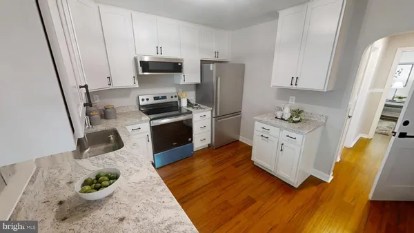 a kitchen with stainless steel appliances a stove a refrigerator a sink a stove and white cabinets