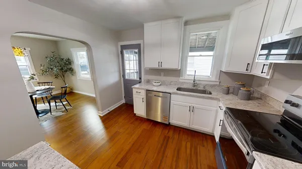 a kitchen with stainless steel appliances granite countertop wooden floors and view living room