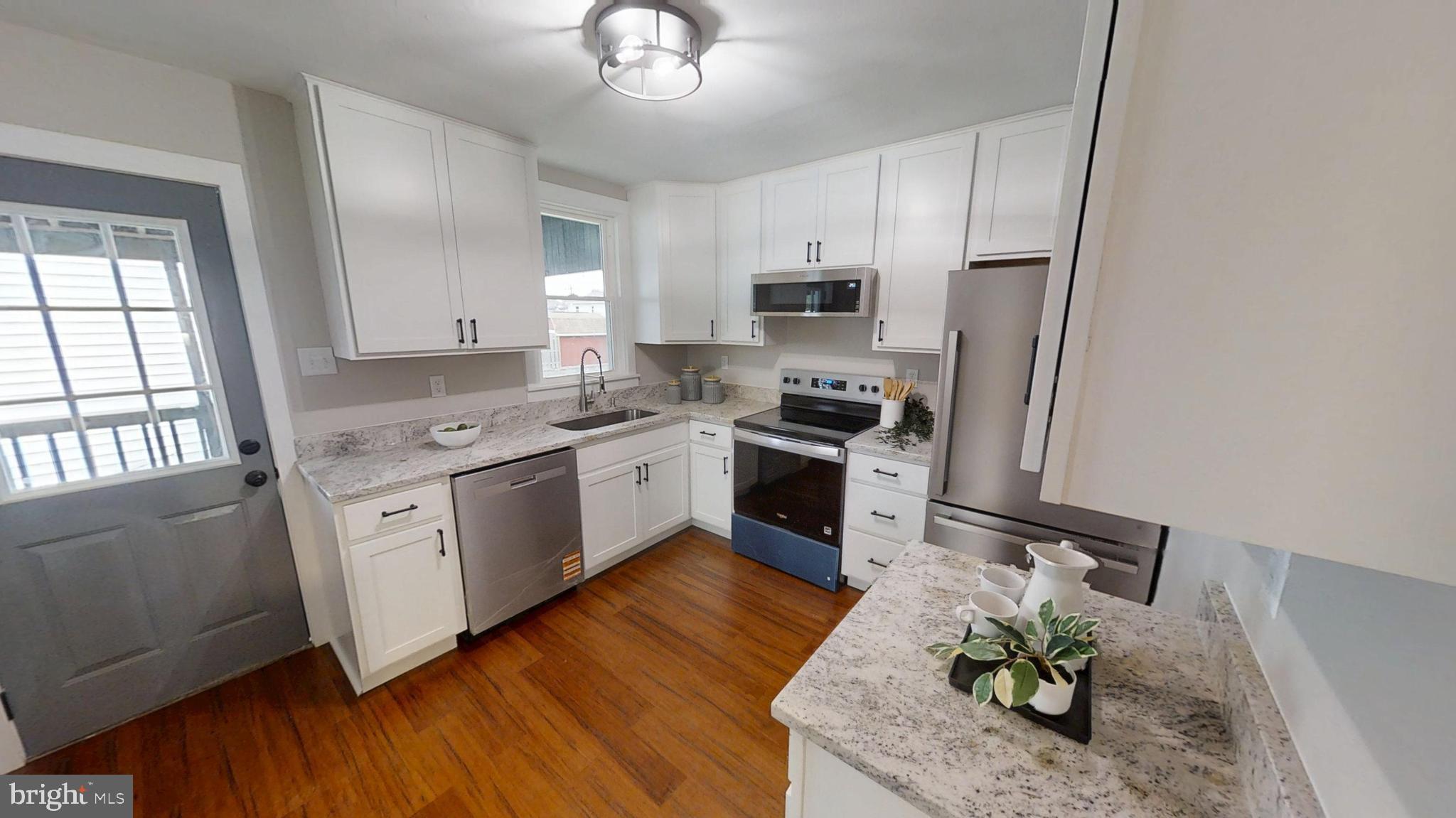 308 Holy Cross Road Baltimore, MD 21225 - Photo 4 of 28 a kitchen with stainless steel appliances granite countertop wooden cabinets a stove a sink and dishwasher with wooden floor