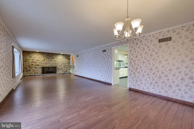 an empty room with wooden floor fireplace and windows