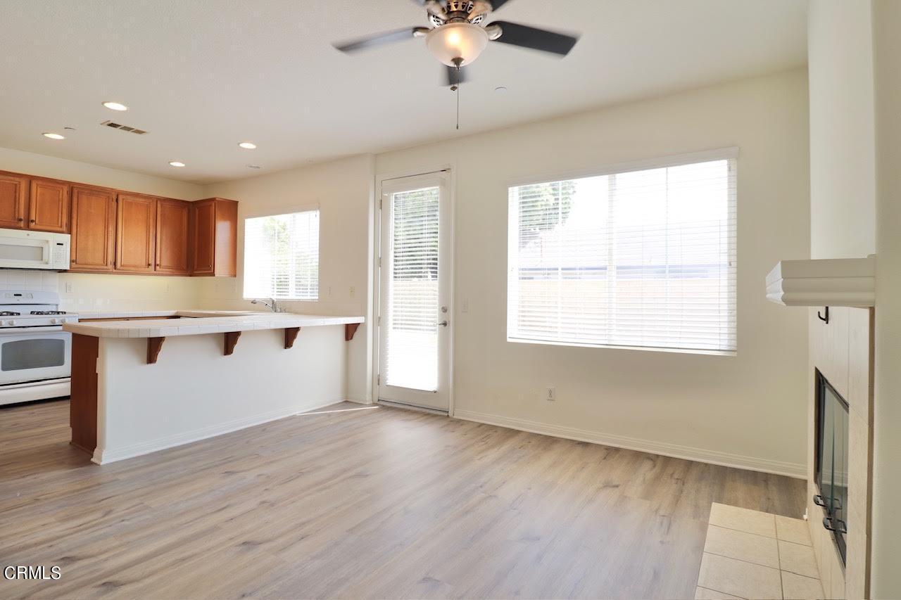 5200 Edgar Street Oxnard, CA 93033 - Photo 6 of 20 a large kitchen with granite countertop a stove a sink a refrigerator and white cabinets with wooden floor