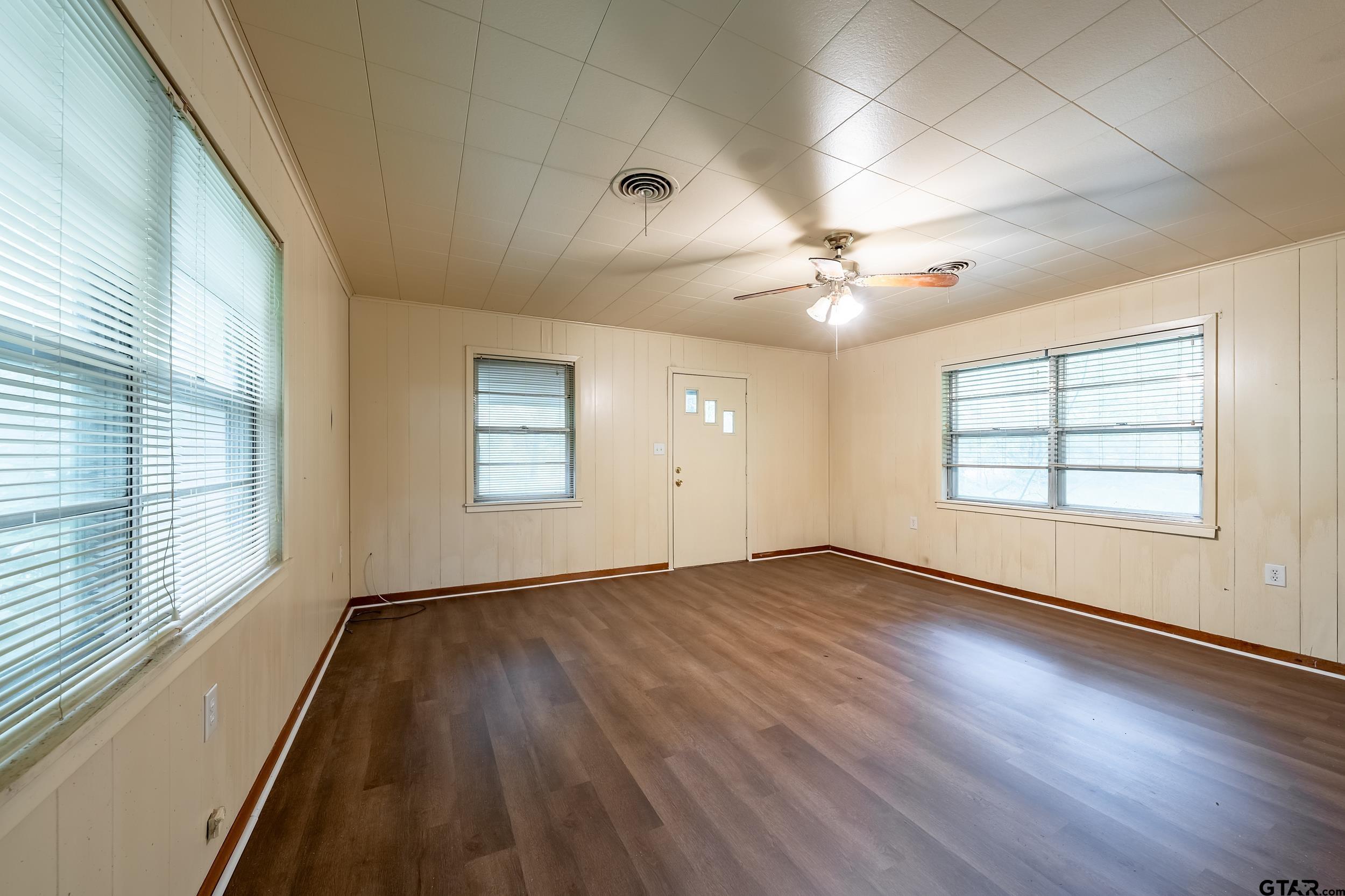 274 West Hill Street Rusk, TX 75785 - Photo 19 of 26 an empty room with wooden floor chandelier fan and windows