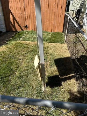 a view of a refrigerator in kitchen and an empty room with wooden floor