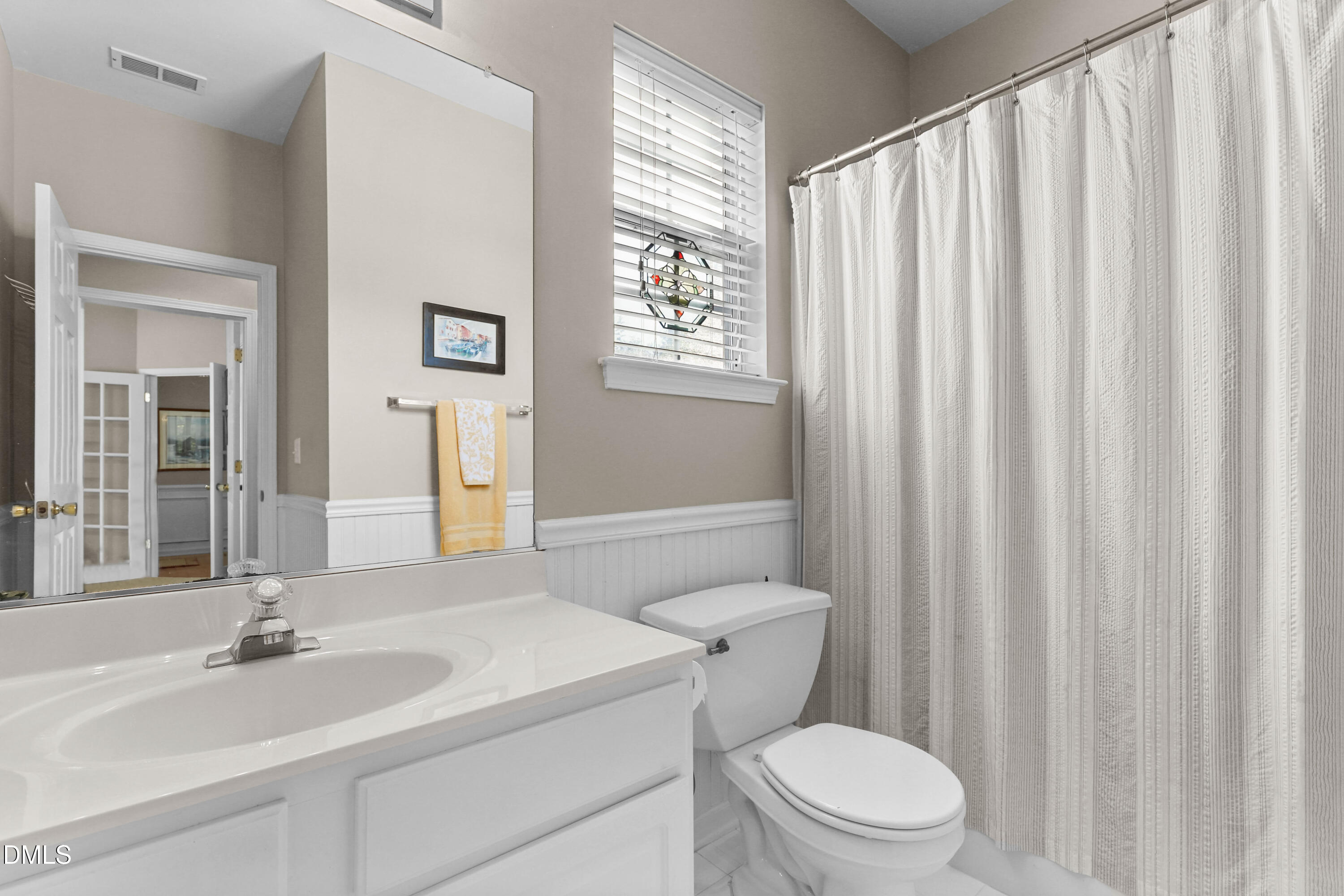 2005 Misty Fog Court Raleigh, NC 27603 - Photo 28 of 42 a bathroom with a sink a toilet a mirror and shower curtain