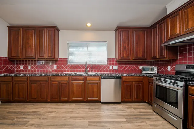 a kitchen with stainless steel appliances granite countertop a stove a sink and a microwave