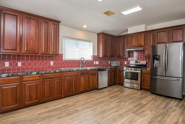 a kitchen with granite countertop stainless steel appliances and wooden cabinets