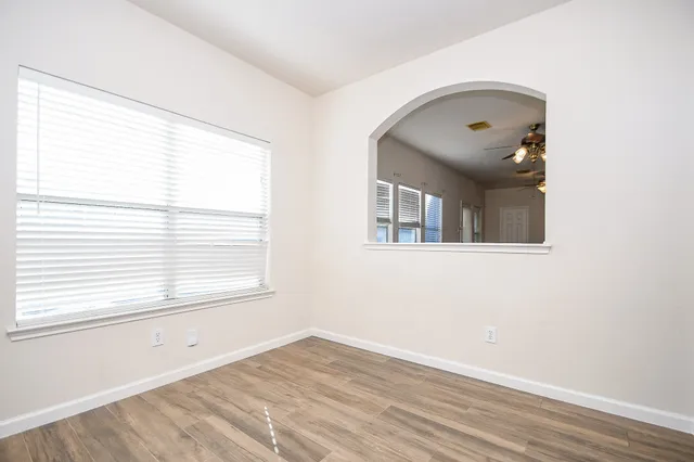 a view of an empty room with wooden floor and a window