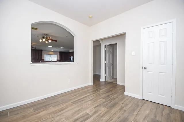 an empty room with wooden floor and a ceiling fan