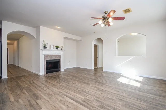 a view of an empty room with a fireplace and wooden floor