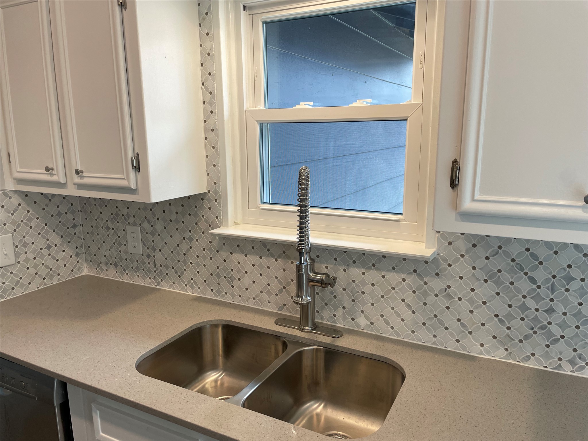 4619 Jinx Avenue, Unit A Austin, TX 78745 - Photo 7 of 21 Kitchen sink area featuring a dual stainless steel sink, a pull-down faucet, light-colored countertops, and a patterned tile backsplash