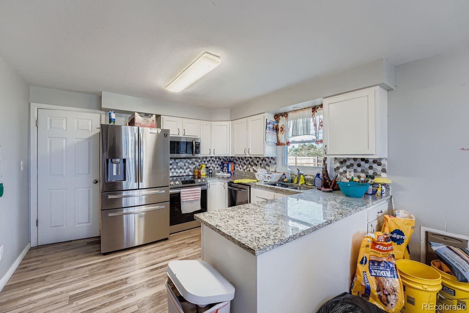361 East Thomas Avenue Byers, CO 80103 - Photo 11 of 28 a kitchen with stainless steel appliances kitchen island granite countertop a refrigerator and a stove top oven