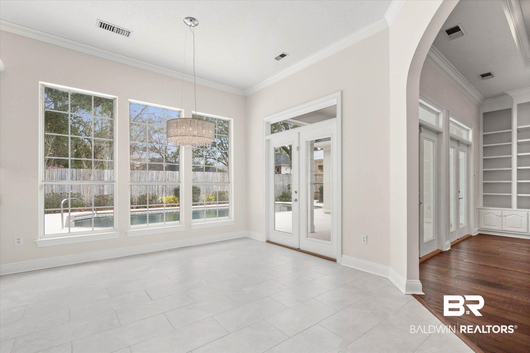 1083 Southern Way Court Mobile, AL 36609 - Photo 13 of 31 Unfurnished dining area with built in shelves, ornamental molding, arched walkways, plenty of natural light, and light tile patterned floors