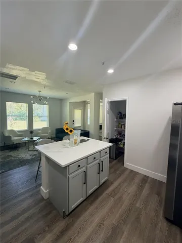 a large white kitchen with a sink a refrigerator and wooden floor