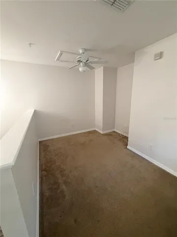 an empty room with a ceiling fan and carpet