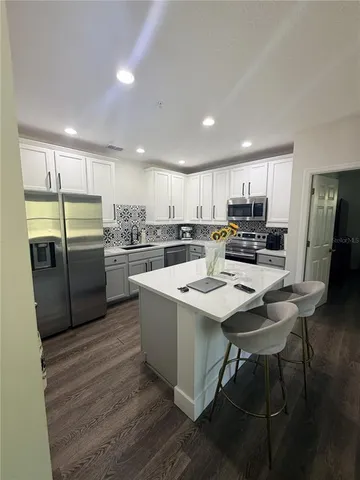 a kitchen with stainless steel appliances a refrigerator a sink a stove a table and chairs