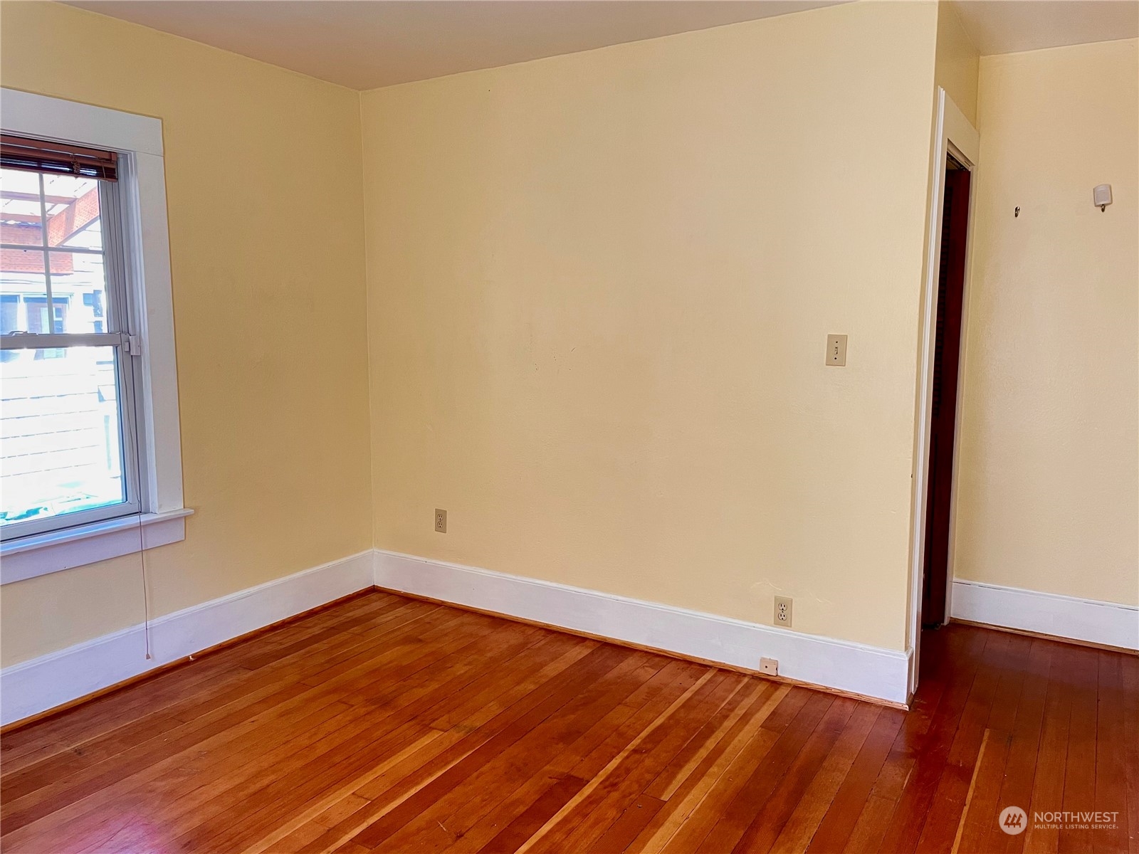825 Northeast 63rd Street Seattle, WA 98115 - Photo 7 of 12 an empty room with wooden floor and windows