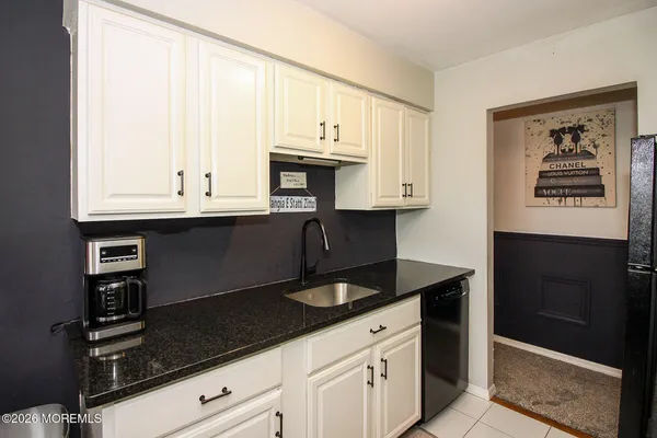 a kitchen with granite countertop white cabinets and black appliances