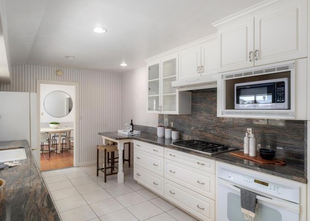 a kitchen with stainless steel appliances granite countertop a stove a sink and a white cabinets