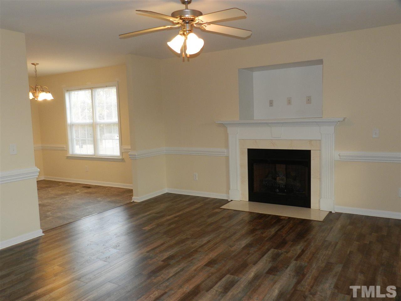 453 Axum Road Willow Spring, NC 27592 - Photo 5 of 17 an empty room with wooden floor fireplace and window