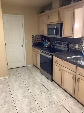 a kitchen with granite countertop a stove a sink and a microwave