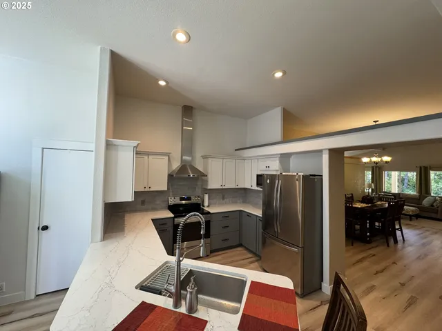a kitchen with stainless steel appliances kitchen island granite countertop a refrigerator and a sink