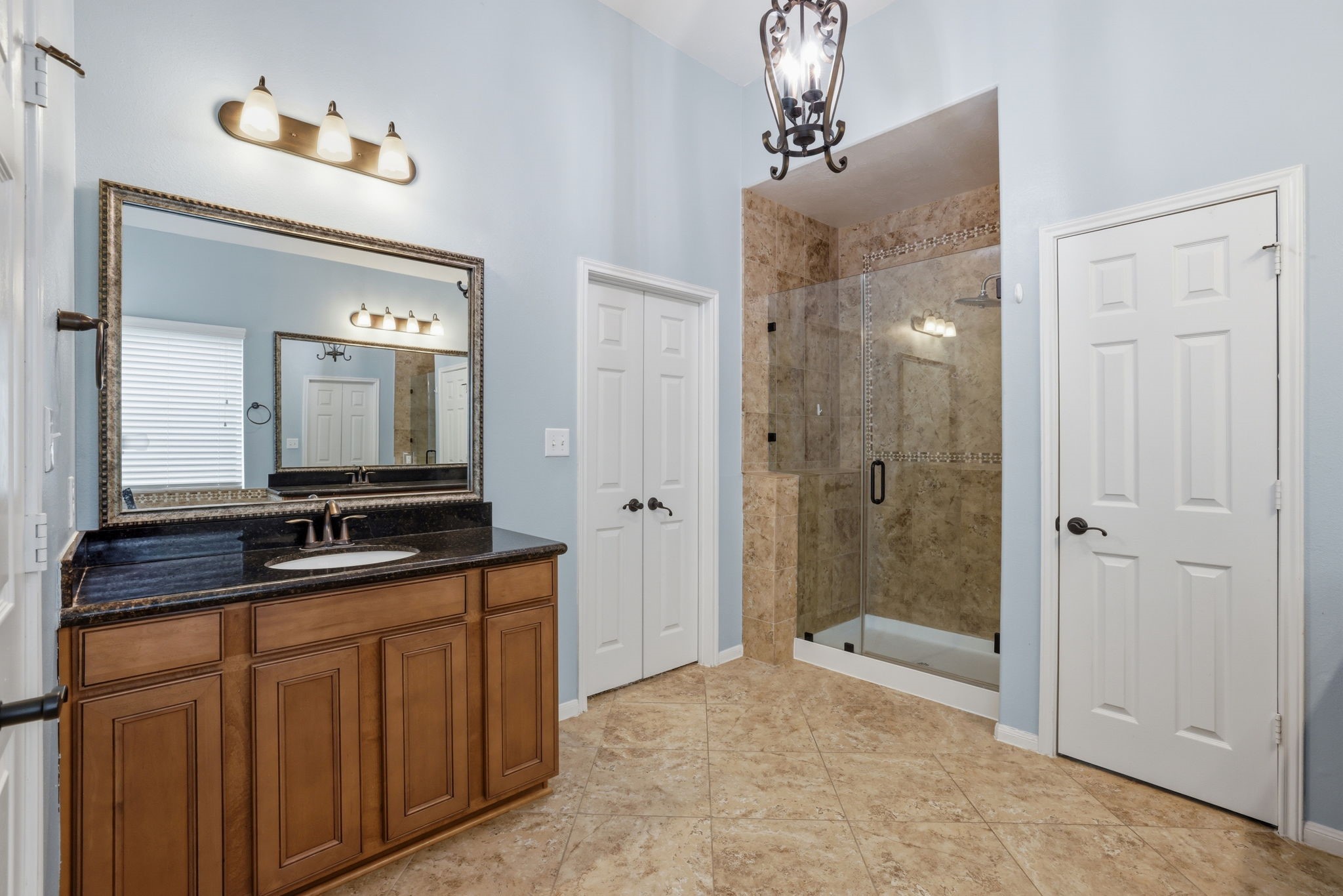 8169 Tranquil Lake Way Conroe, TX 77385 - Photo 15 of 26 a bathroom with a granite countertop sink a mirror and a shower
