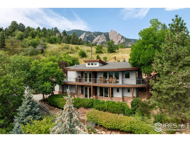 a view of a big house with a big yard and large trees