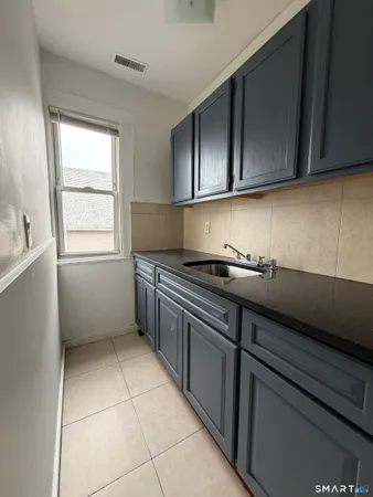 a kitchen with granite countertop a sink a stove and cabinets