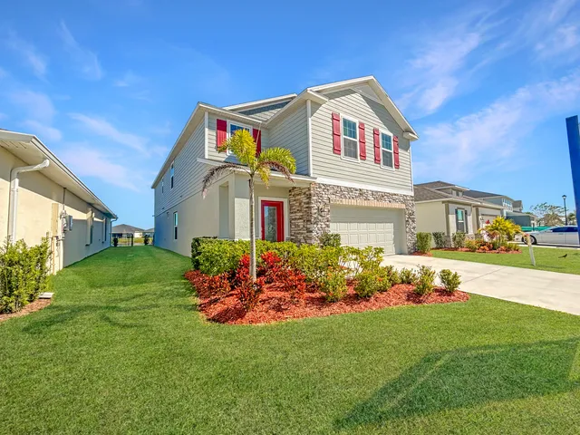 a front view of a house with a big yard and potted plants