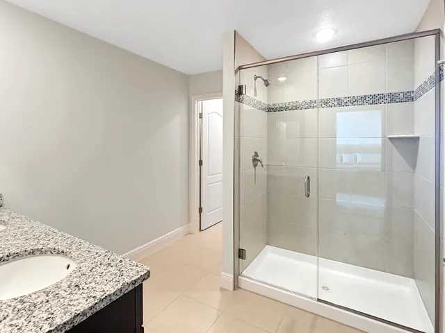 a bathroom with a granite countertop shower and a sink