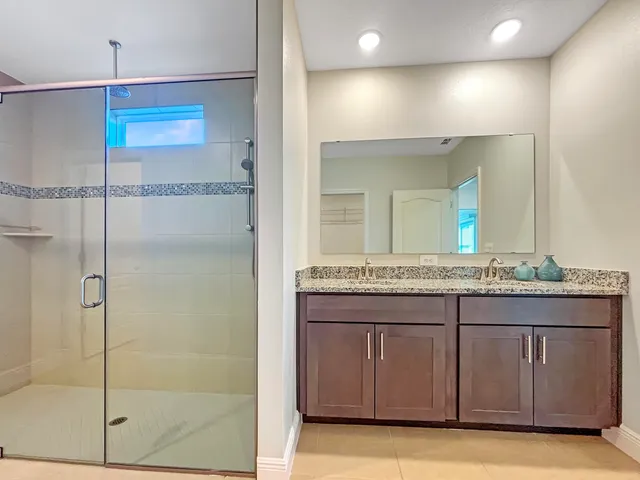 a bathroom with a granite countertop sink a mirror and a shower