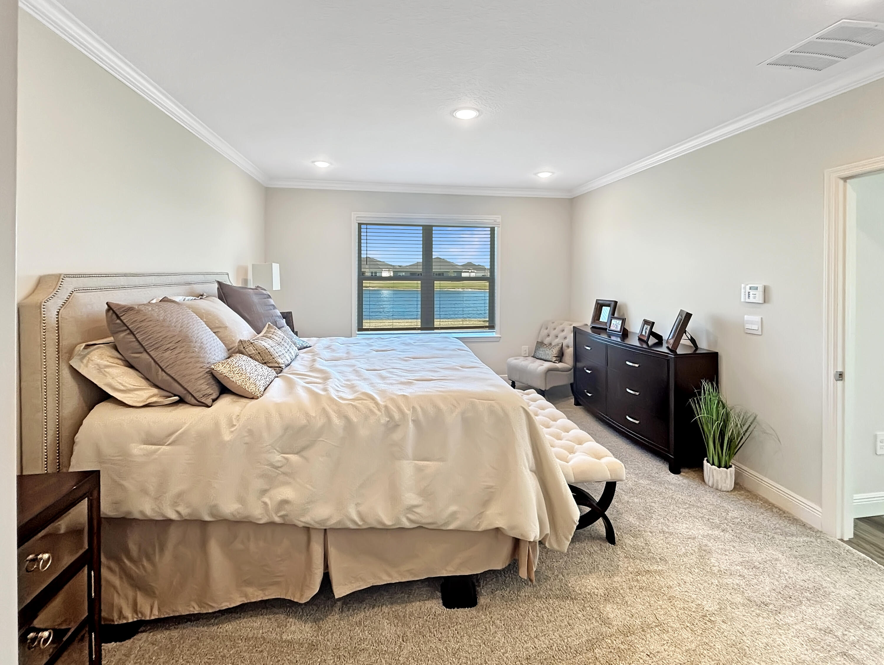 9399 Southwest Serapis Way Port Port St. Lucie, FL 34987 - Photo 24 of 43 a bed sitting in a bedroom next to a window and dresser