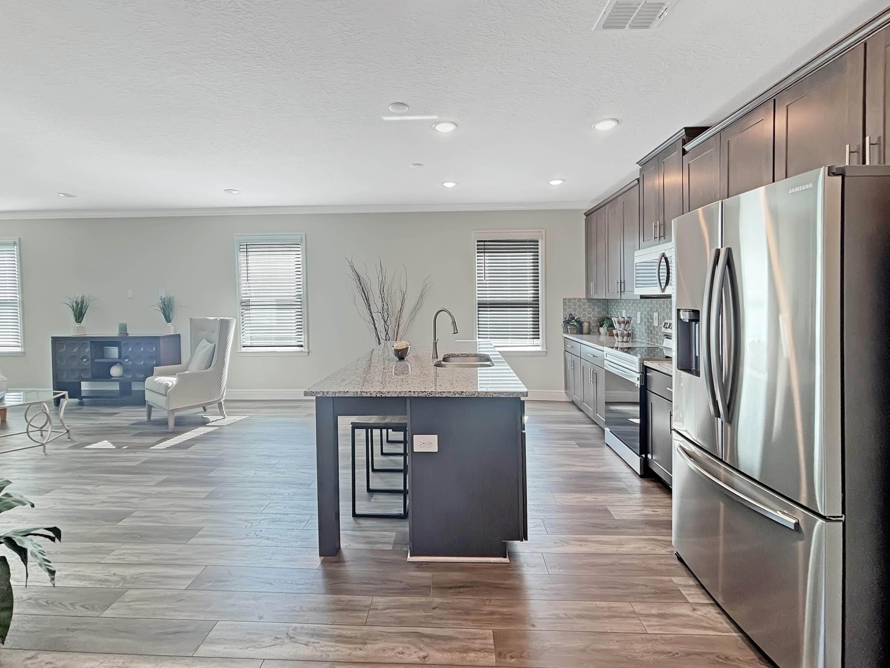 9399 Southwest Serapis Way Port Port St. Lucie, FL 34987 - Photo 10 of 43 a kitchen with stainless steel appliances granite countertop a refrigerator a stove and a sink with wooden floor