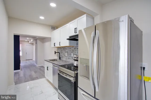 a kitchen with stainless steel appliances granite countertop a refrigerator and a stove top oven