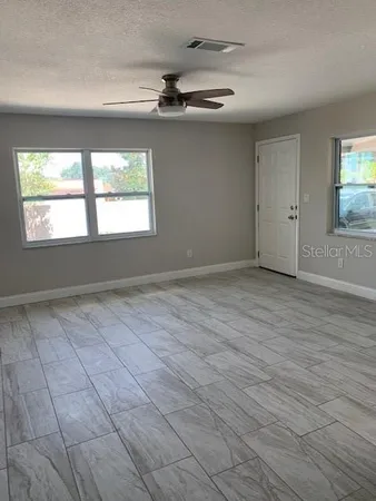 an empty room with wooden floor and windows