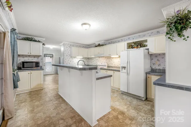 a kitchen with refrigerator a microwave and white cabinets