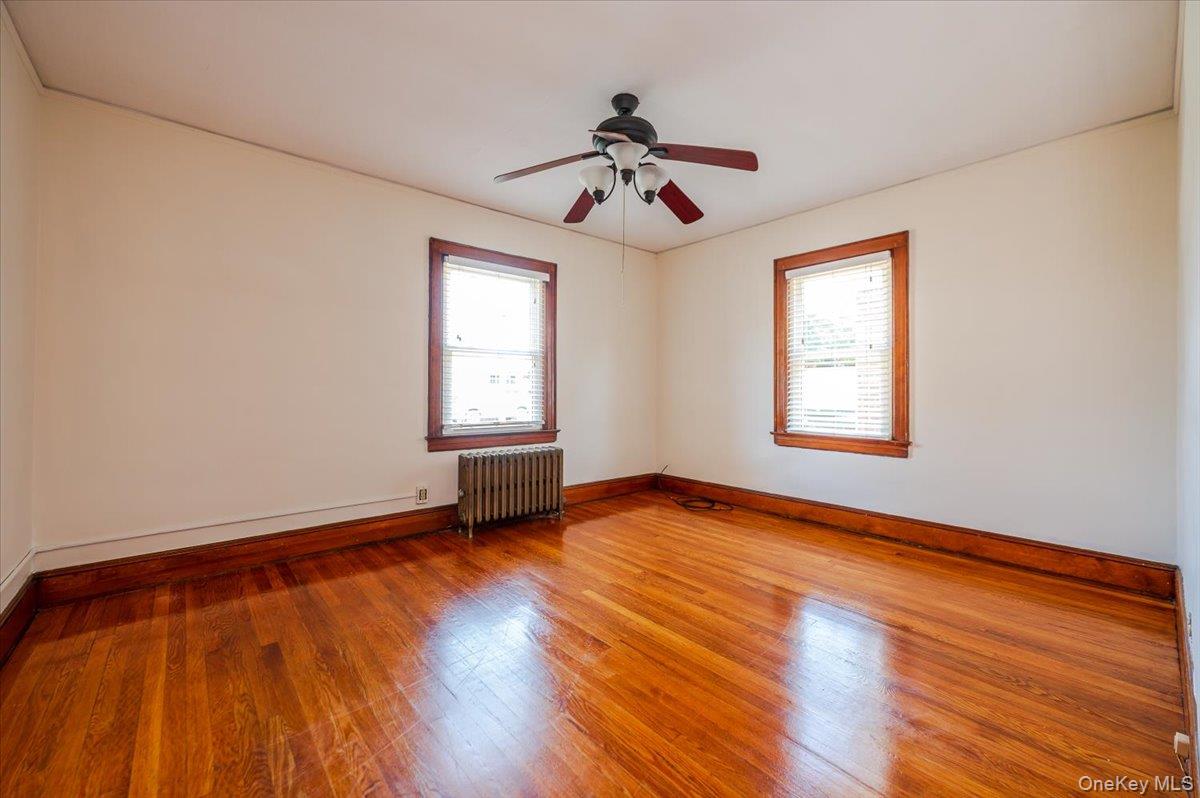 715 Iris Street Franklin Square, NY 11010 - Photo 9 of 20 an empty room with wooden floor ceiling fan and windows