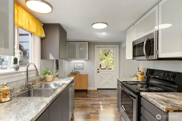 a kitchen with stainless steel appliances granite countertop a sink a stove top oven a counter space and cabinets