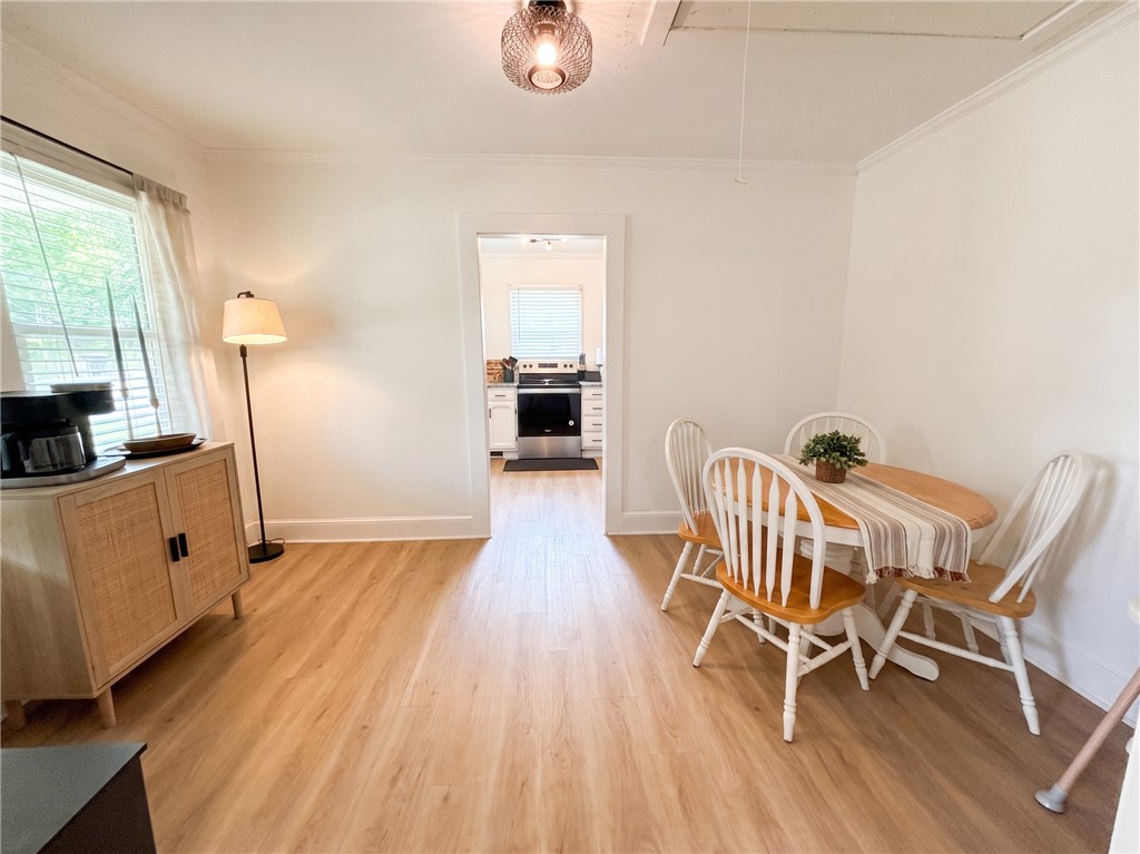 710 O Neal Street Belton, SC 29627 - Photo 7 of 18 Warm wood-look flooring and a cozy dining area define this inviting living space, with a kitchen peeking through an open doorway.