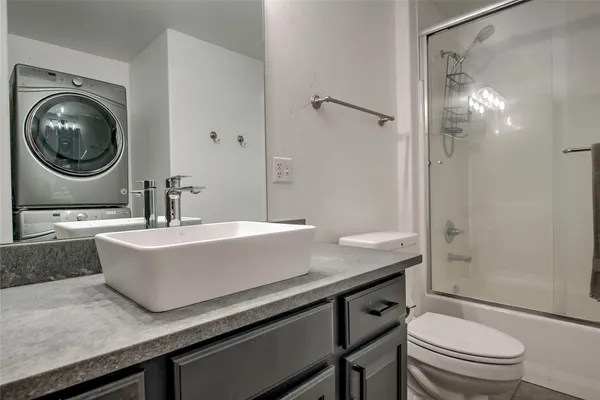 a bathroom with a granite countertop sink a toilet a mirror and shower