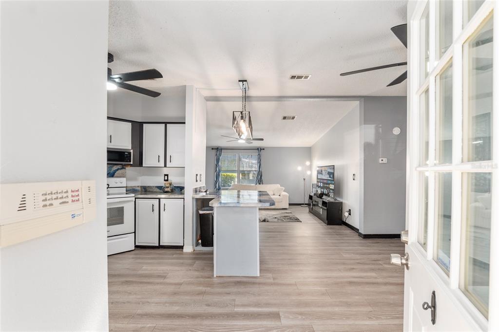 6832 Northeast 3rd Place Ocala, FL 34470 - Photo 12 of 70 a kitchen with a refrigerator a stove cabinets and living room view