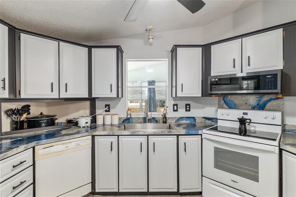 6832 Northeast 3rd Place Ocala, FL 34470 - Photo 19 of 70 a kitchen with white cabinets and white appliances