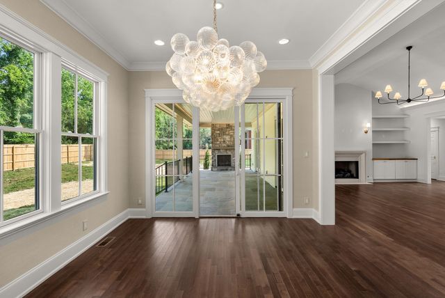 a view of an empty room with wooden floor and windows